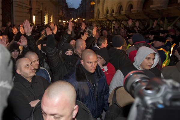 A MEASZ tüntetését megzavarók magasba emelik a karjukat Budapesten, az Új Színháznál