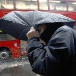 People shelter under an umbrella during heavy rain in central London